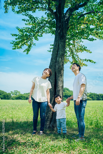 木の下で並ぶ親子3人  © maru54