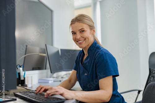 Nurse on Duty working on computer at the Reception Desk in modern clinic. High quality photo