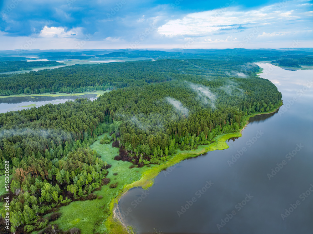 Big lake with green shores with morning fog in dawn, aerial landscape. Recreation concept. Aerial view