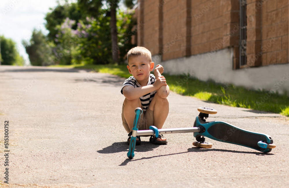 The little boy fell off the scooter and injured himself. Children's ...