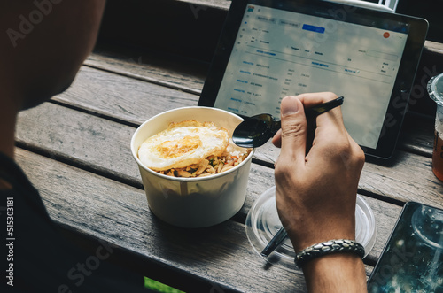 seen from behind an asian man having breakfast with a bowl of rice with eggs before starting work