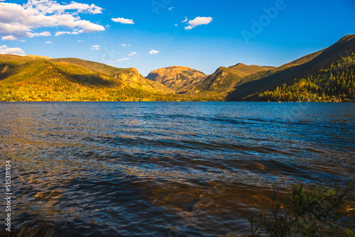 Panoramic view of mountain range by the lake in Colorado, USA, at sunset; waves in foreground and blue sky in background photo
