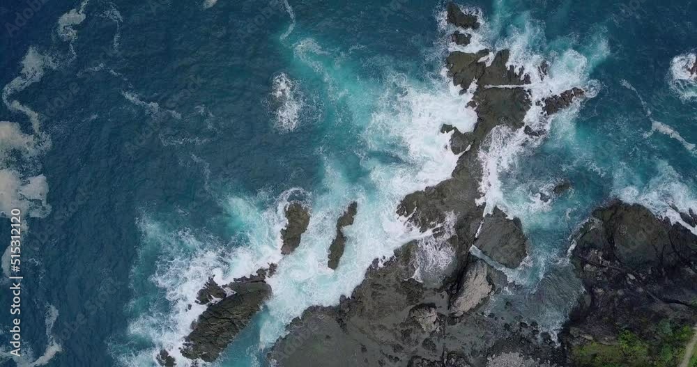 overhead shot of big waves of Indian Ocean hitting boulder and rocks in the beach in sunny condition weather - Pengilon Hill, Indonesia, Asia