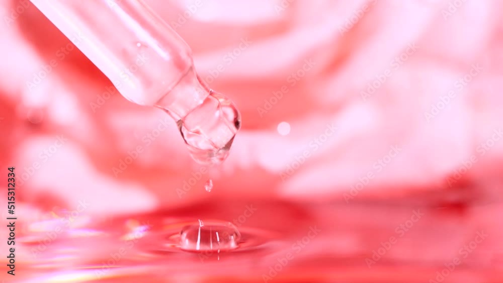 Pink serum fluid, oil drop from dropper falling in water on blurred rose flower