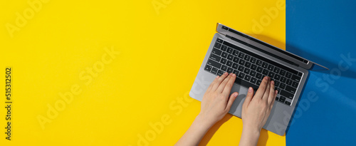 Female hands and laptop on yellow - blue background