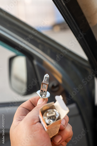 A halogen light bulb in a man's hand. A professional worker changes the new halogen lamps of the car. Car repair.