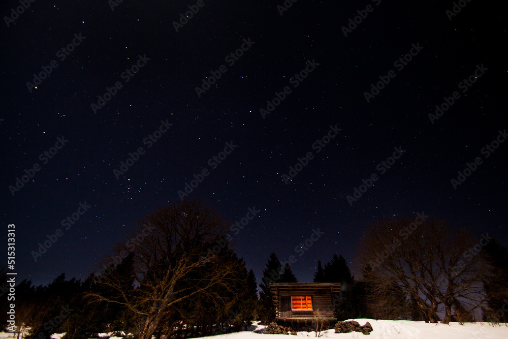 Log cabin shelter in the wild mountains at Ballon de Servance at night with stellar sky during winter in Vosges, France