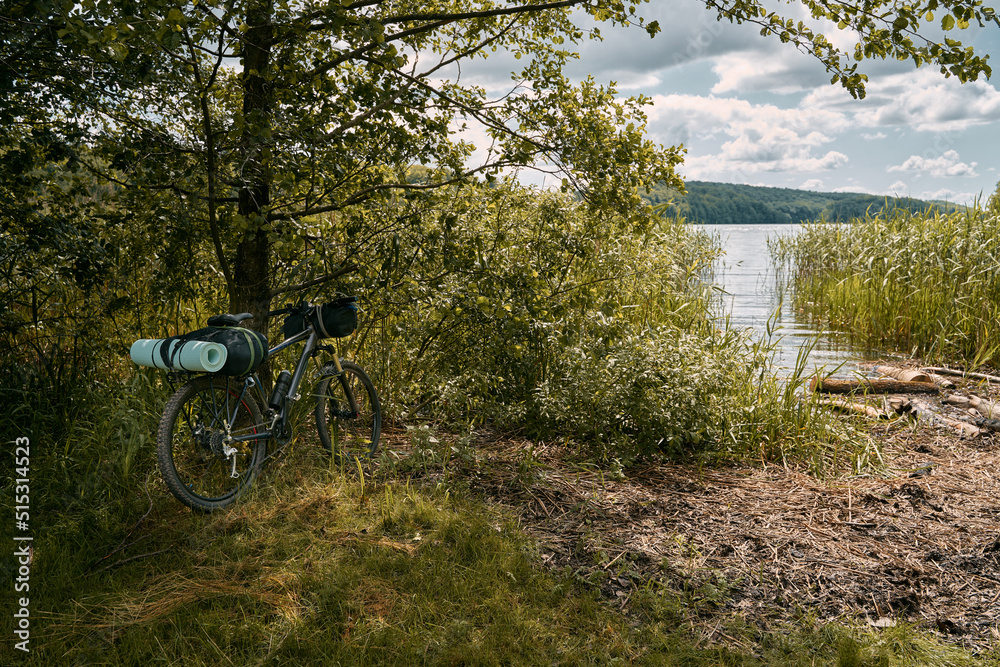 A gravel bicycle with camping equipment for outdoor leisure activities. Summer adventures on the bike. Two travel mats on the front rack of the cycle. A gravel bicycle with camping equipment for outdoor leisure activities. Summer adventures on the bike. Two travel mats on the front rack of the cycle.