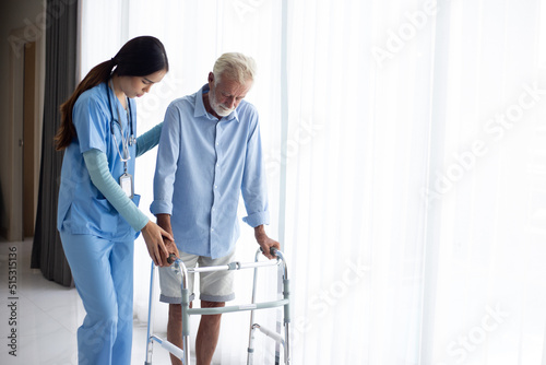 Fényképezés female doctor helping active senior man to walk with walker at home