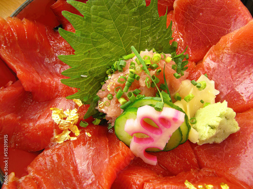 close-up vibrant color of freshness red tuna slices topping on japanese rice sashimi don with cucumber ginger and wasabi