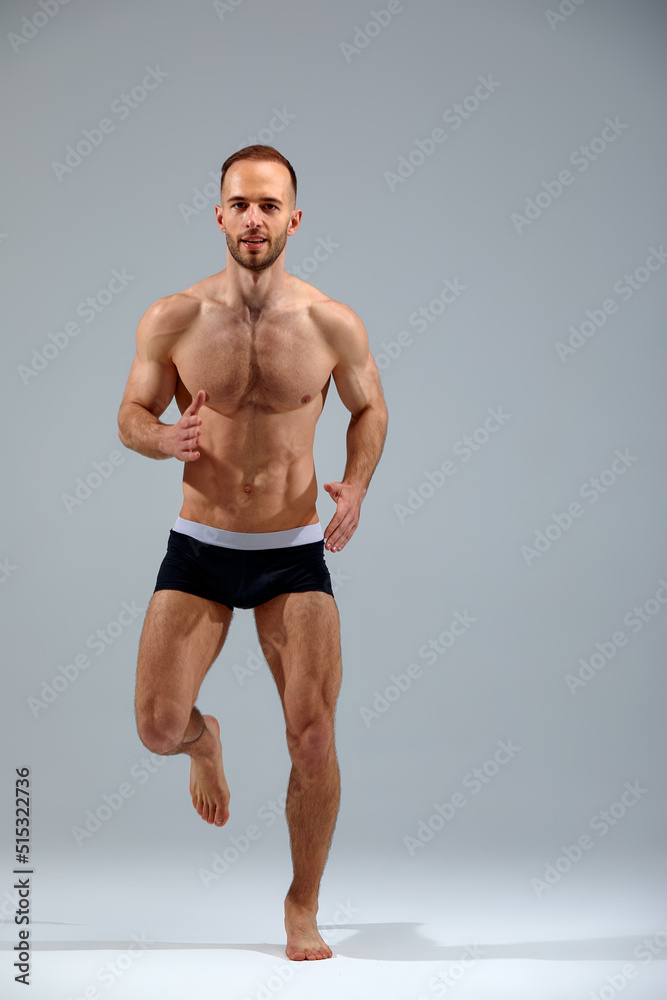 Full length portrait of a confident young sportsman shirtless jumping isolated over white background