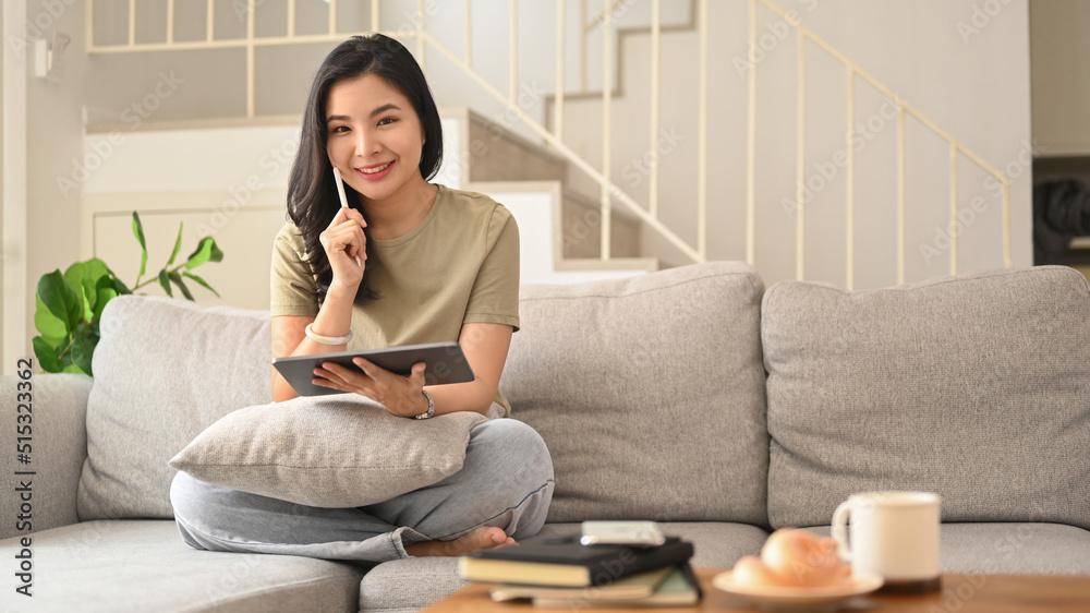 Young asian woman in casual clothes surfing internet on digital tablet at home Young asian woman in casual clothes surfing internet on digital tablet at home