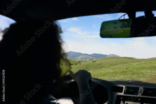 A panorama of beautiful green hills. A summer landscape in the Crimea. View from a car, driven by a woman. Front view. © Anastasiia