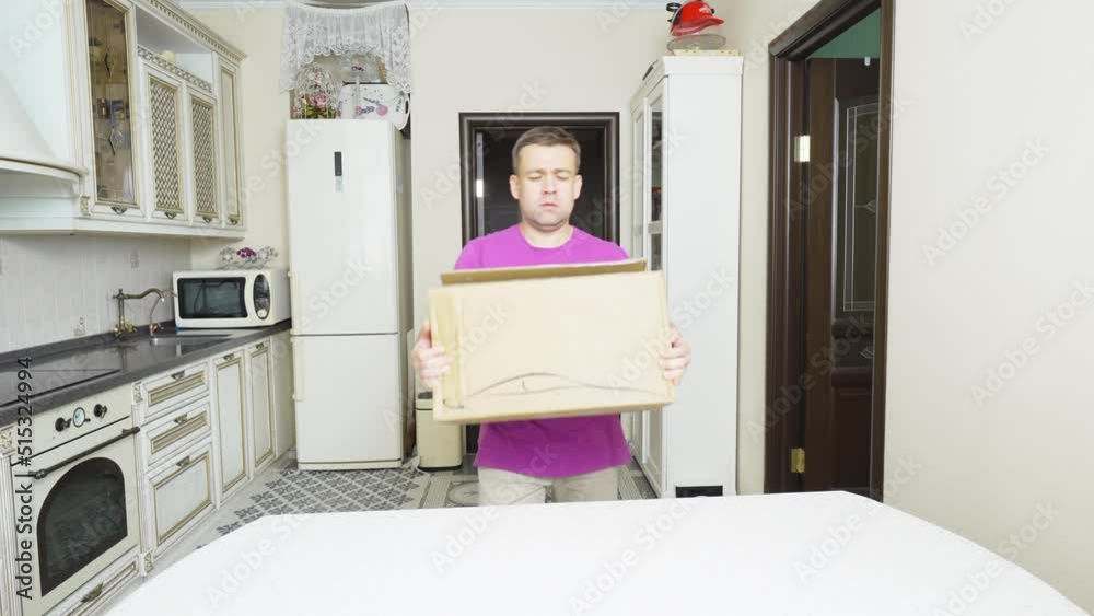 a distressed man brings in, puts and opens a box with an electric car charger. a distressed man brings in, puts and opens a box with an electric car charger.