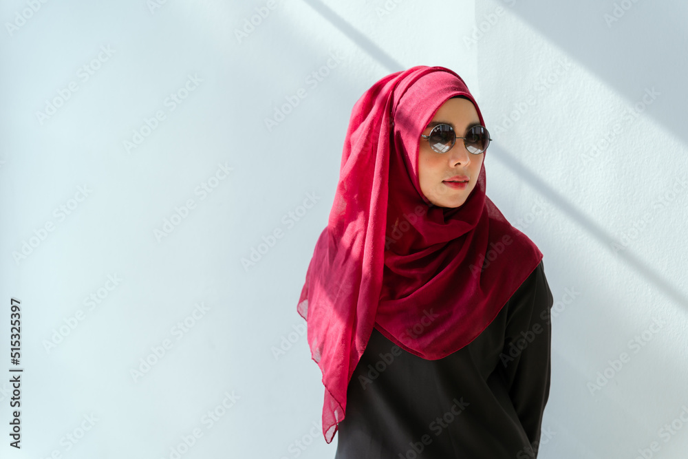Beautiful young working woman in hijab, suit and eyeglasses standing in office, smiling. Portrait of confident muslim business woman. Modern office with big window. Beautiful young working woman in hijab, suit and eyeglasses standing in office, smiling. Portrait of confident muslim business woman. Modern office with big window.