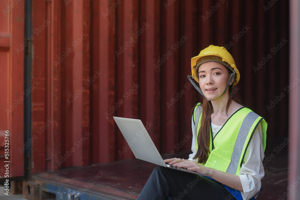 Happy and beautiful Young Caucasian women worker sitting at work with a laptop to inspect the stock of export goods at the containers before delivering to overseas customers at port warehouse. Happy and beautiful Young Caucasian women worker sitting at work with a laptop to inspect the stock of export goods at the containers before delivering to overseas customers at port warehouse.