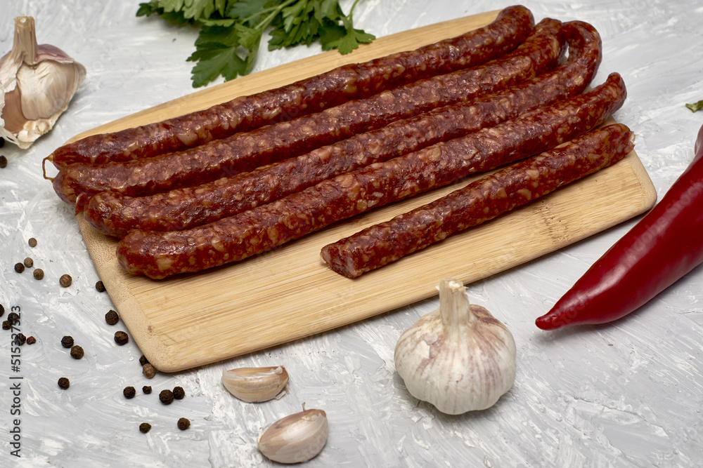 spicy smoked sausages on a cutting board next to red pepper garlic spices and herbs on the table spicy smoked sausages on a cutting board next to red pepper garlic spices and herbs on the table