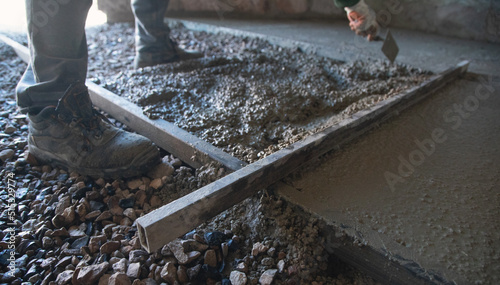 Construction worker aligns concrete screed floor. photo