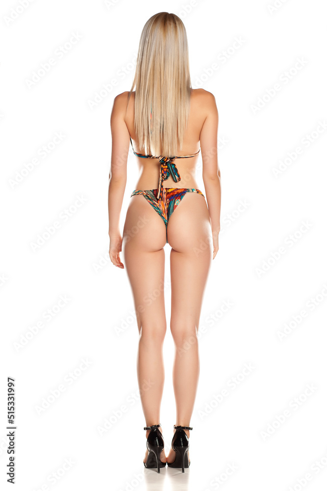 Rear view of blonde woman in swim suit, isolated on white.