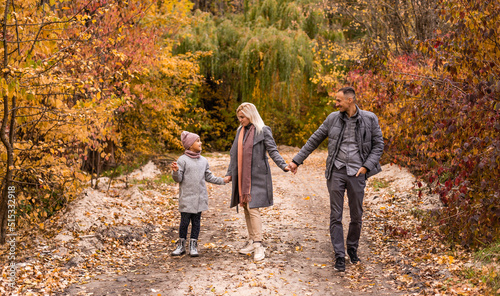 A Family of four enjoying golden leaves in autumn park © Angelov