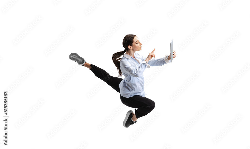 Portrait of young woman, employee typing on tablet isolated over white studio background. In a jump