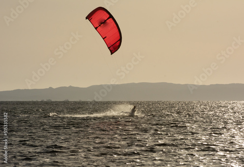 Expert Kitesurfer Planing with Sea Watrer Splashes during Golden Hour