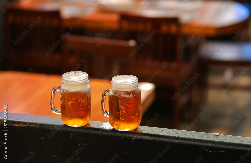 Two cold two mugs of beer inside an American pub Two cold two mugs of beer inside an American pub