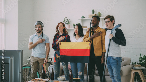 Φωτογραφία Multi ethnic group of friends sport fans listening and singing German national a