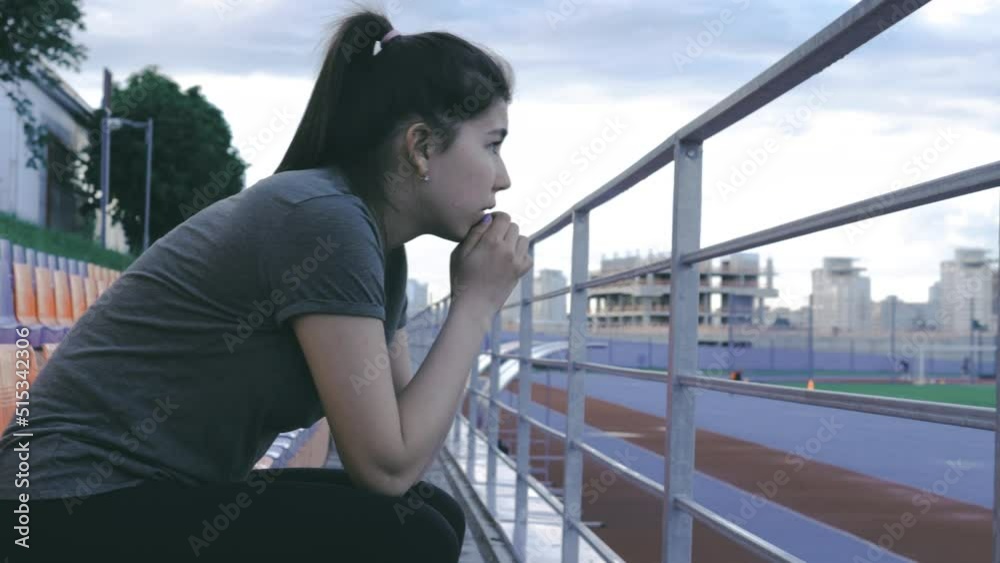 Astonished amazed young woman watching match, looking at athletes on the stadium. Asian pretty sporty female Astonished amazed young woman watching match, looking at athletes on the stadium. Asian pretty sporty female