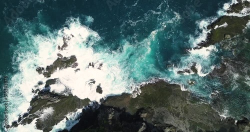 Static overhead shot of sea waves of Indian Ocean hitting boulder and rocks in the beach in sunny condition weather - Pengilon Hill, Indonesia, Asia photo