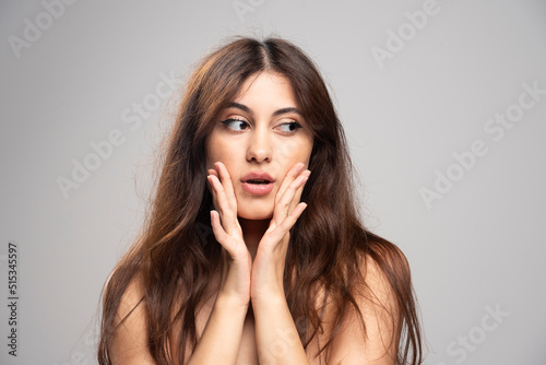 A young woman looking away and touching her face