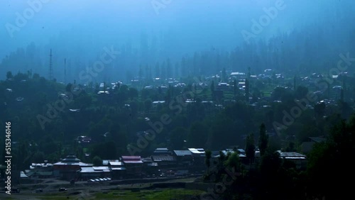Slow motion shot of city with lush green mountains in hilly area of Pakistan at evening.