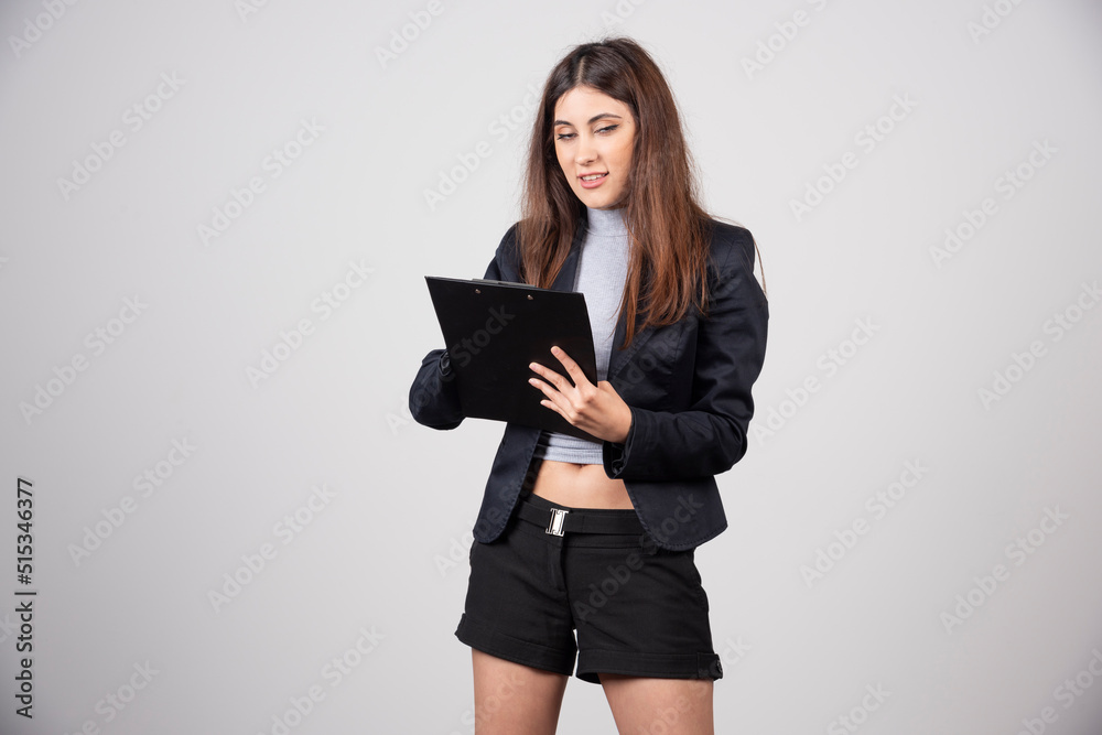 A young business woman writing in clipboard isolated on gray background A young business woman writing in clipboard isolated on gray background