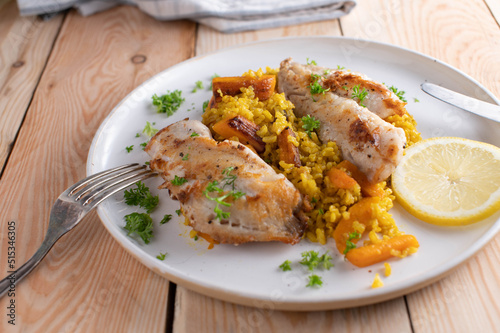 Healthy fish dish with redfish fillet served with turmeric rice and roasted carrots