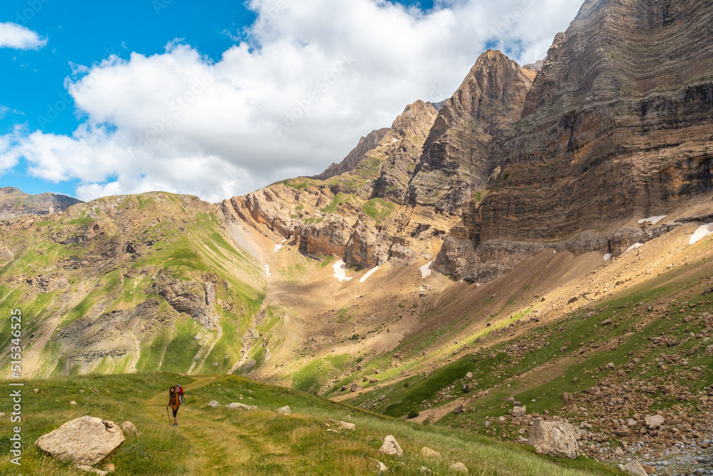 Fototapeta premium A young woman walking through the mountains with her son in the backpack in the Ripera valley, Pyrenees