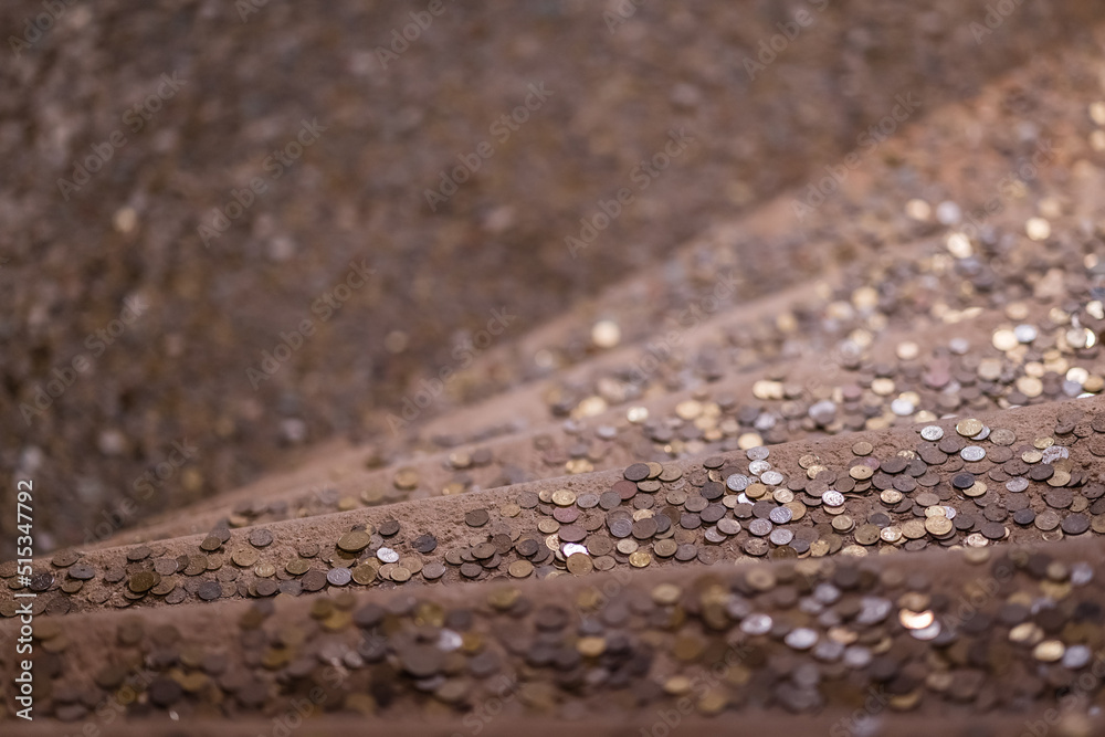 Vertical shot of shiny coins thrown on the stairsfor good luck