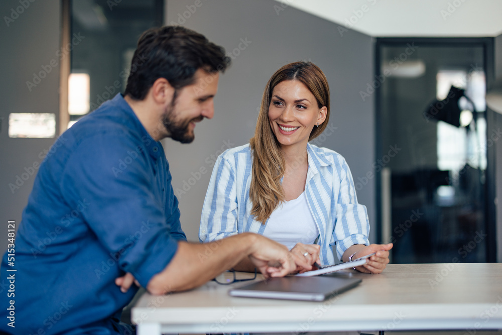 Focus on the smiling businesswoman, looking at her male boss, making plans together. Focus on the smiling businesswoman, looking at her male boss, making plans together.