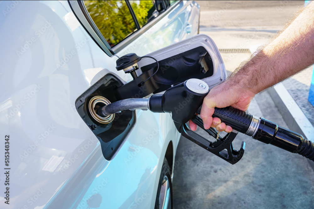 Hand of a man filling the fuel tank of the car at a gas station.