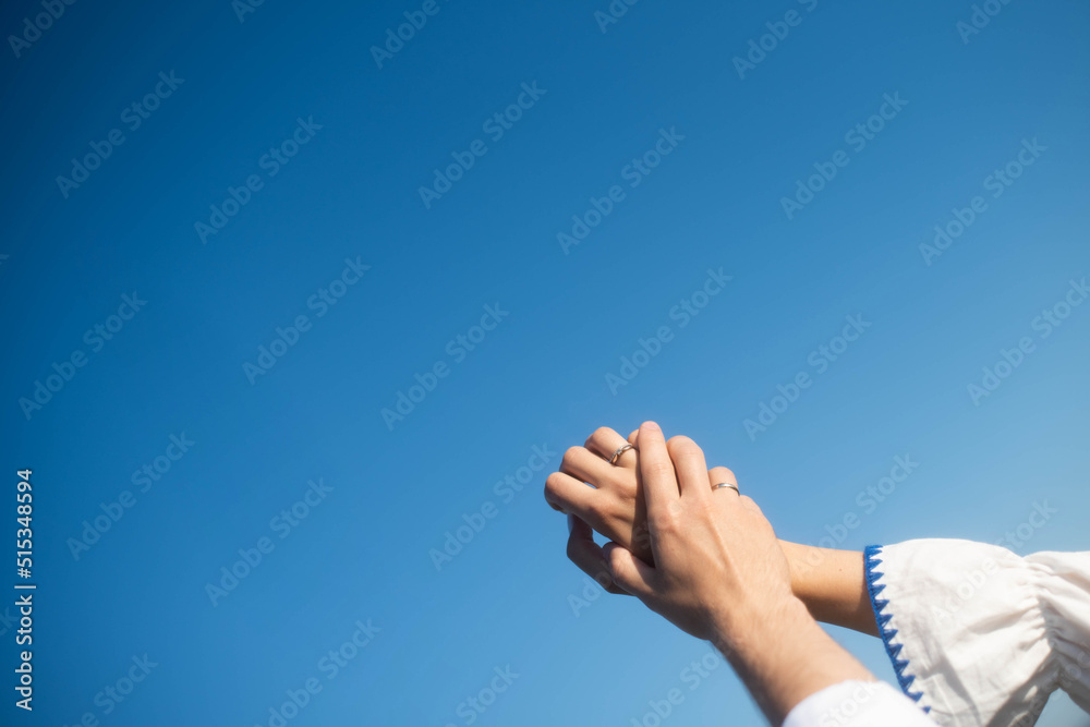 The hands of maried on the background of the sky. Sunny day . Young hands.Blue background hands up in the air. Selective focus The hands of maried on the background of the sky. Sunny day . Young hands.Blue background hands up in the air. Selective focus