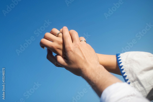 The hands of fiance and bride on the background of the sky. Sunny day . Young hands.Blue background hands up in the air. Selective focus