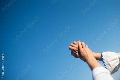 The hands of the betrothed on the background of the sky. Sunny day . Young hands.Blue background hands up in the air. Selective focus