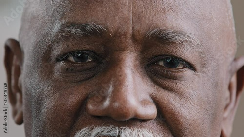 Close-up male dark eyes wrinkled face African American old man looking at camera with sad expression elderly senior man poor vision trouble eyesight problem ophthalmology insurance health care service