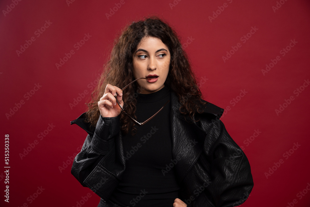 Woman in all black outfit holding glasses and posing Woman in all black outfit holding glasses and posing