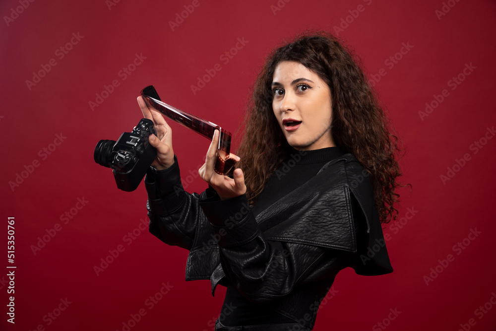 Woman in all black outfit holding a photo tape with a camera Woman in all black outfit holding a photo tape with a camera