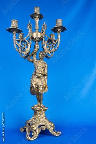 classic bronze chandelier with a figure of woman, ancient candlestick studio photo, antique candlestick isolated, brass chandelier, one vintage candlestick, bronze candle tree on blue background photo