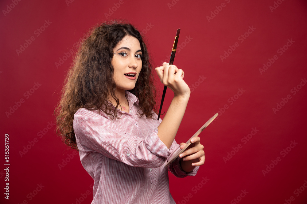 Young woman holding paint brush and paint palette Young woman holding paint brush and paint palette