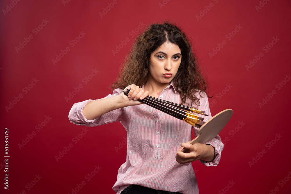 Young woman holding paint brushes and paint palette Young woman holding paint brushes and paint palette