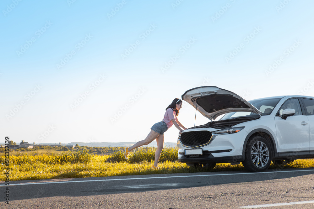 woman looking at car engine call road assistant