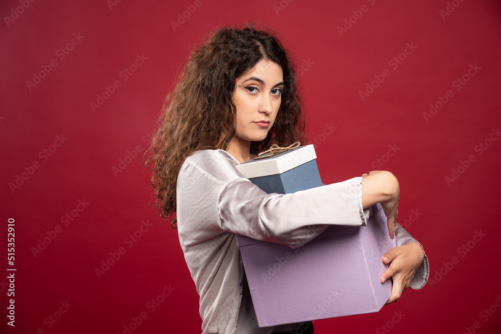 Portrait of young woman holding gift boxes tightly Portrait of young woman holding gift boxes tightly