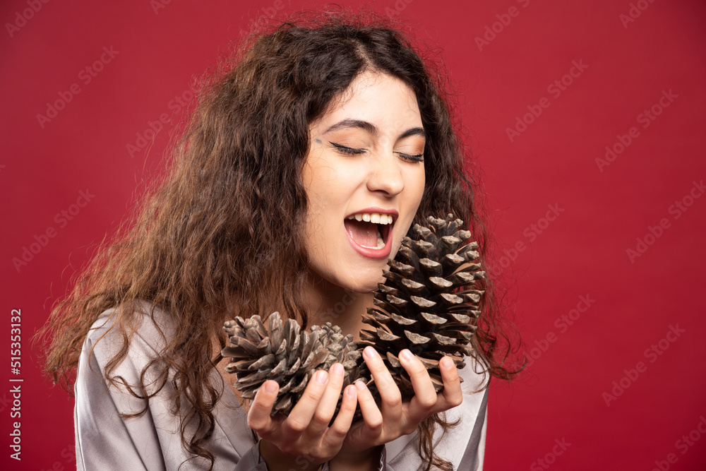 Beautiful girl looking at pinecones on red background Beautiful girl looking at pinecones on red background